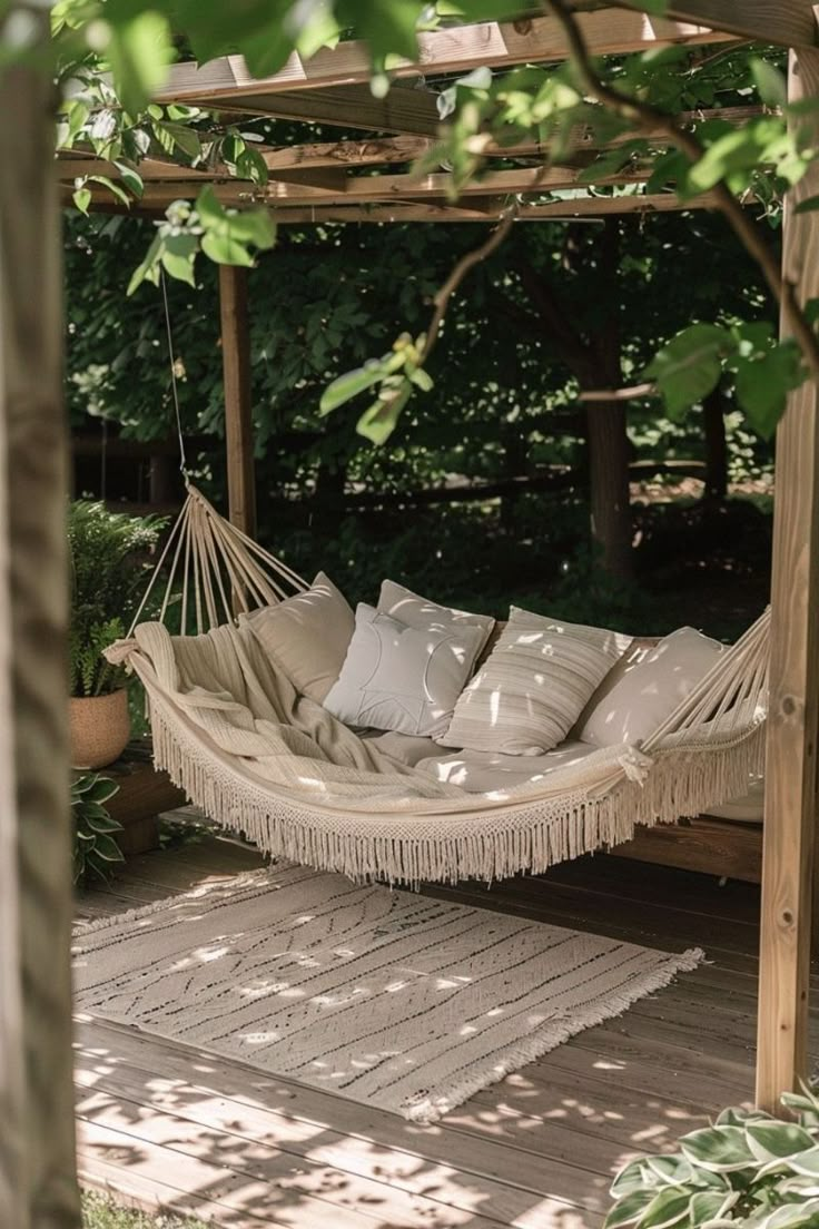 a hammock hanging from a pergolated area with pillows on the ground