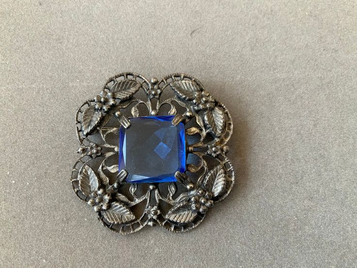 Beautiful blue stone brings brilliance to this old brooch. It measures 1.75 inches in width and length. Antique, and so pretty. Great gift for Mother's Day! Formal Blue Gemstone Brooch, Formal Blue Gemstone Brooches, Vintage Blue Brooches For Jewelry Making, Blue Gemstone Brooch For Anniversary, Blue Gemstone Brooches For Anniversary, Victorian Blue Brooch For Formal Occasions, Blue Victorian Brooch For Formal Occasions, Antique Jeweled Brooches For Gifts, Blue Victorian Brooches For Formal Occasions