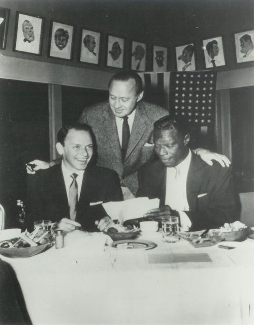 three men sitting at a table with food in front of them