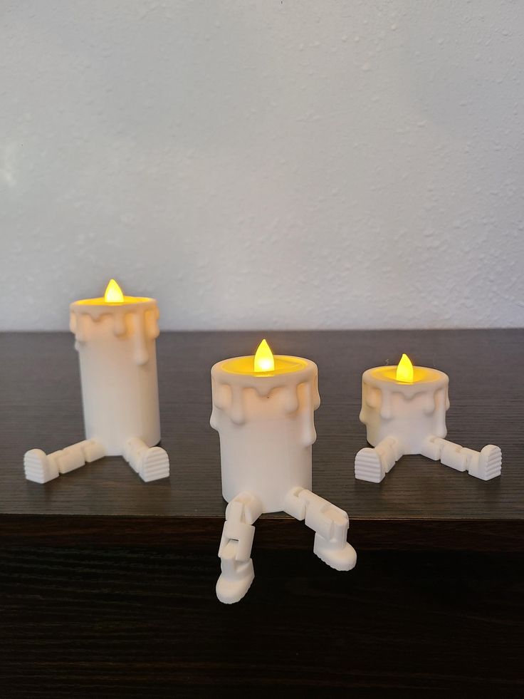 three white candles sitting on top of a wooden table