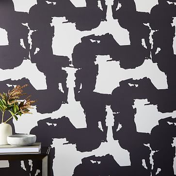 a black and white wall with an abstract pattern painted on it, next to a vase filled with flowers