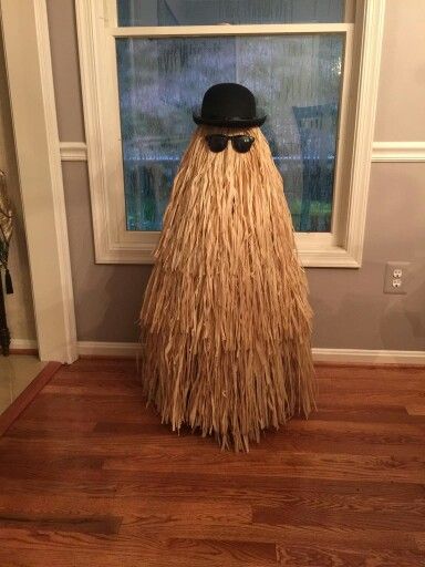 a man in a hat and long beard standing next to a window