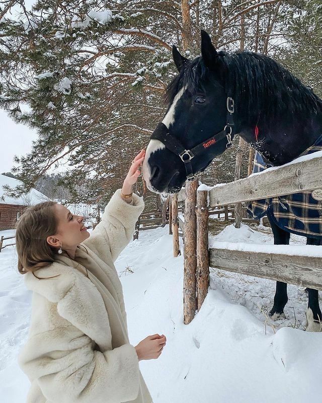 a woman petting a black horse in the snow