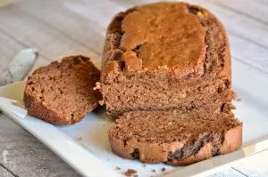 sliced loaf of chocolate banana bread on a white plate with two slices cut off the side