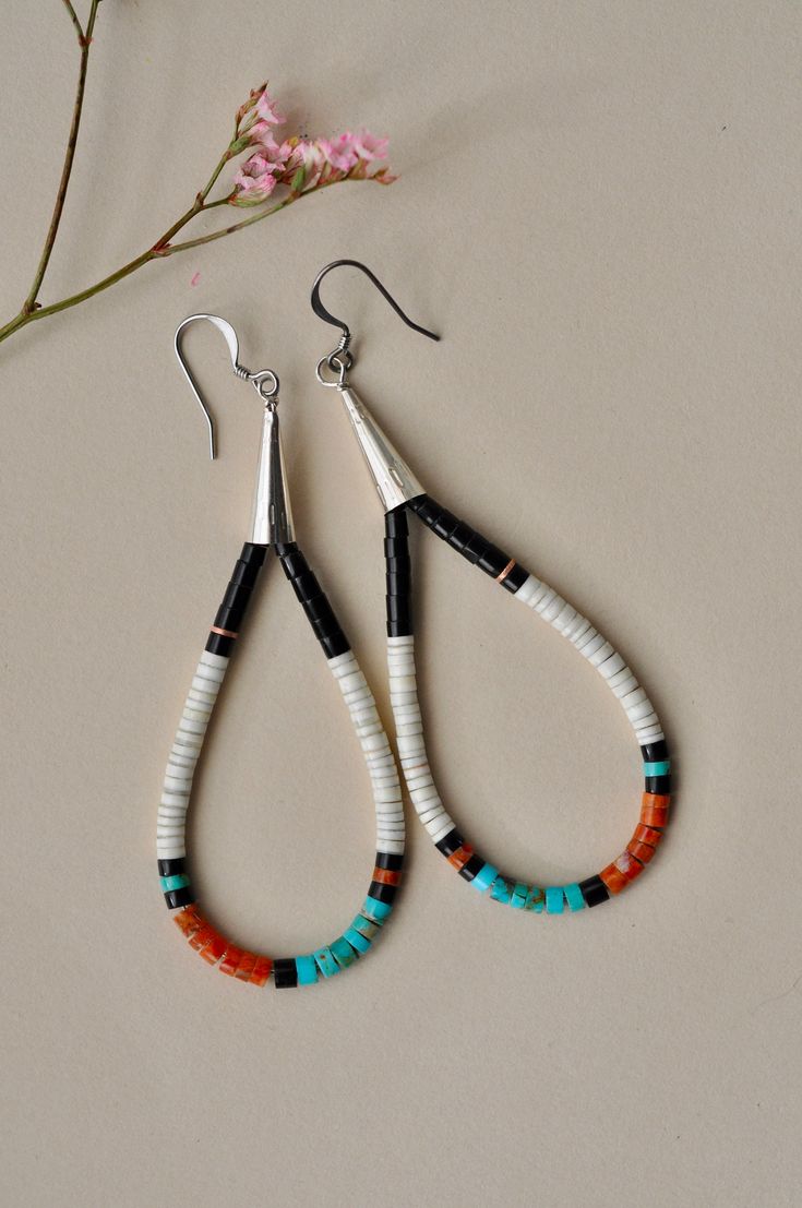 two pairs of beaded earrings sitting on top of a table next to a flower