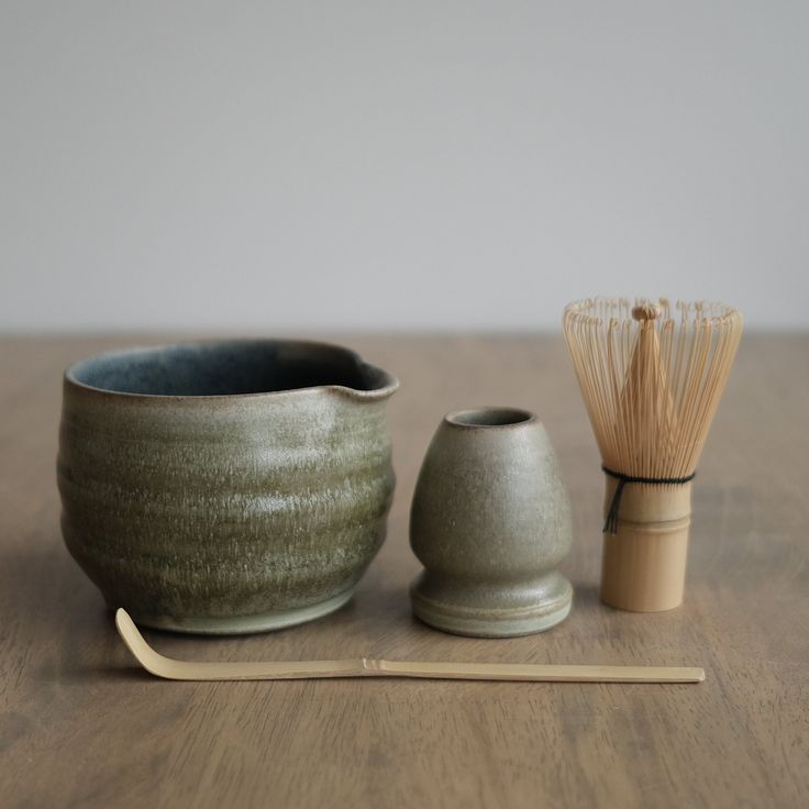 a wooden table topped with two ceramic bowls and a bamboo matchstick next to it