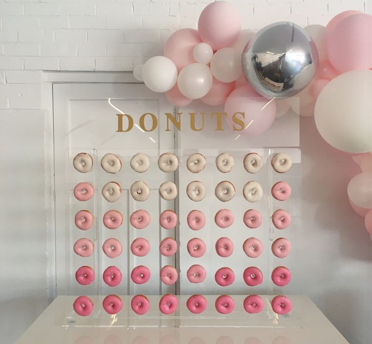 a table topped with donuts next to balloons and a sign that says donuts