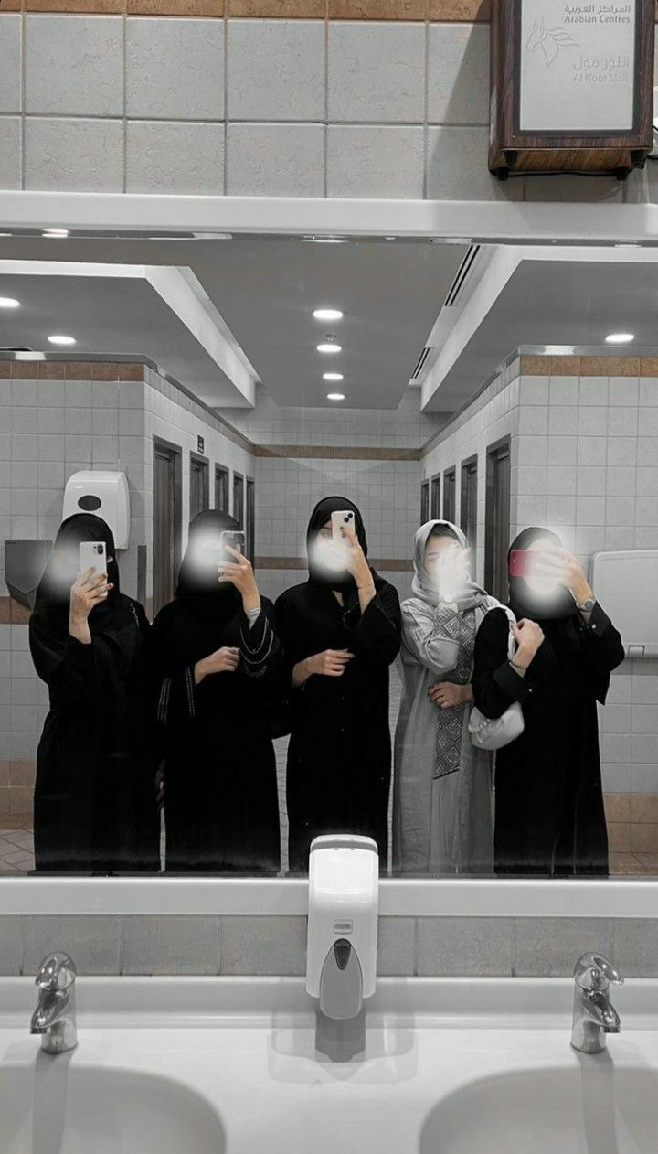 a group of women standing in front of a mirror with their faces covered by blindfolds