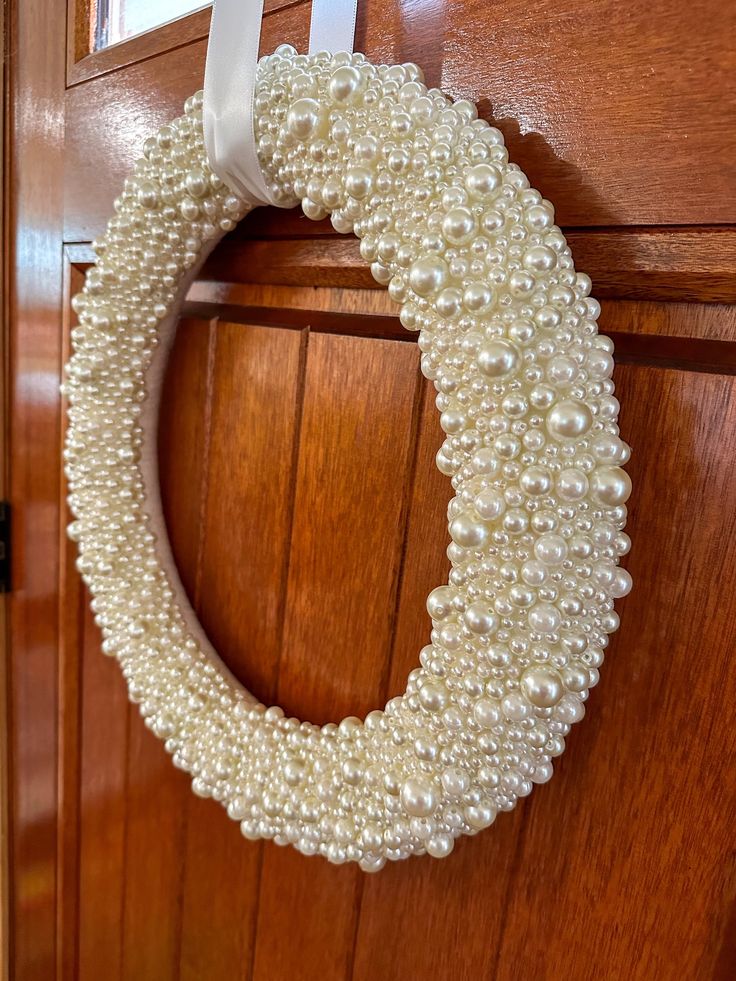 a close up of a wreath on a door with white pearls hanging from it's side