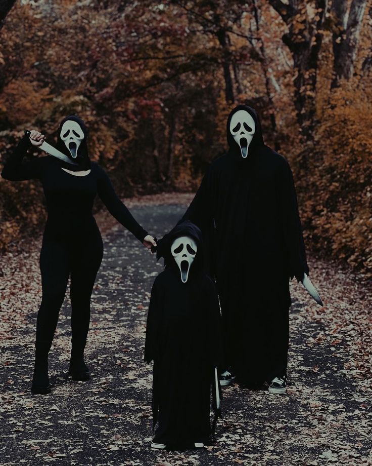 three people dressed in black holding hands with white faces