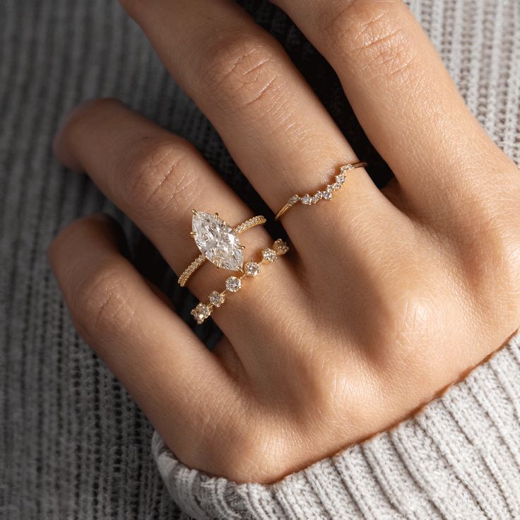 a woman's hand with two rings on her fingers and the ring has a pear shaped diamond