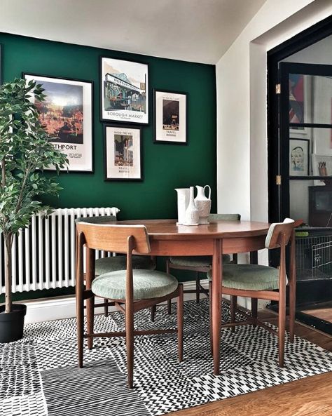 a dining room with green walls and pictures hanging on the wall above the dinning table