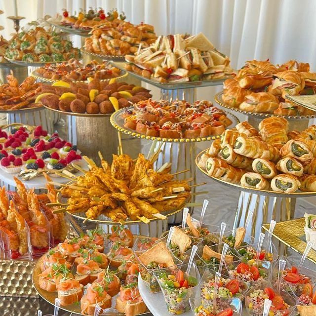 a table filled with lots of different types of food on top of plates and trays