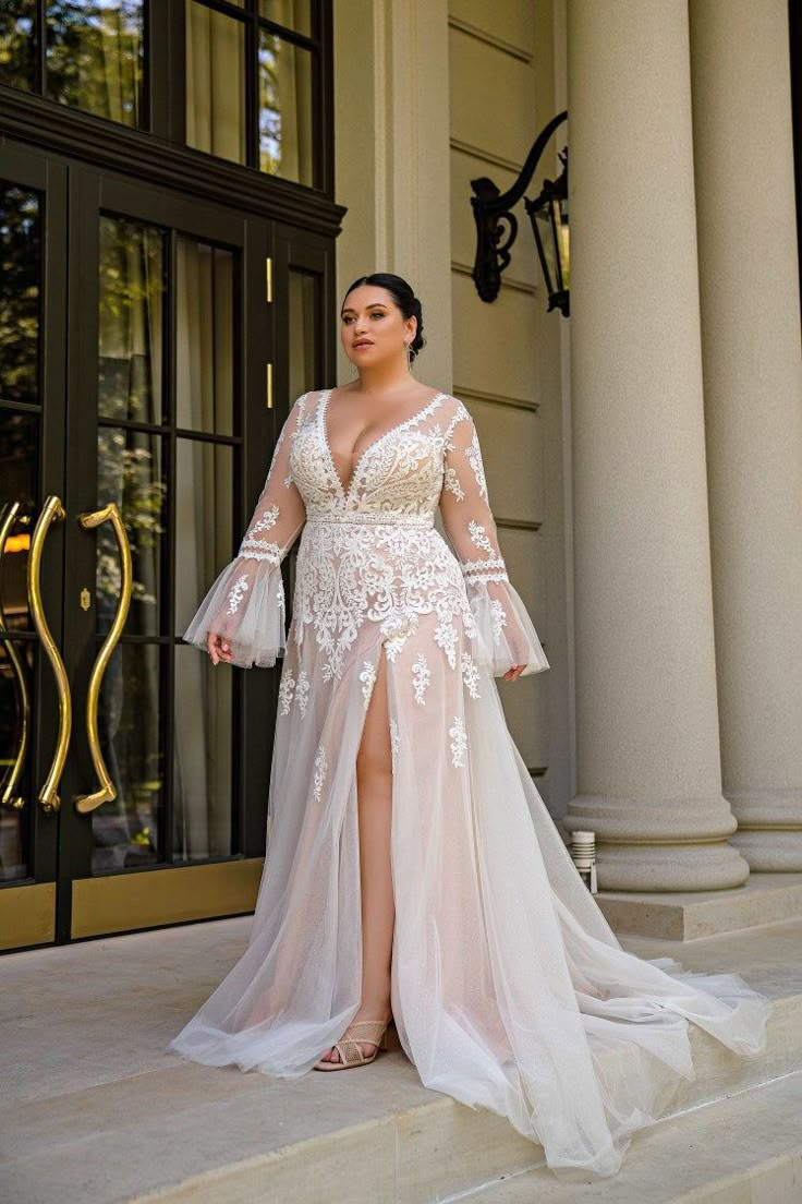 a woman standing on steps wearing a dress with long sleeves and an open slited skirt