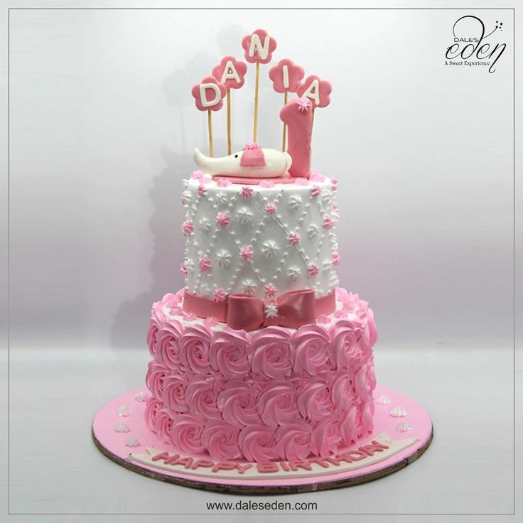 a three tiered cake with pink and white frosting