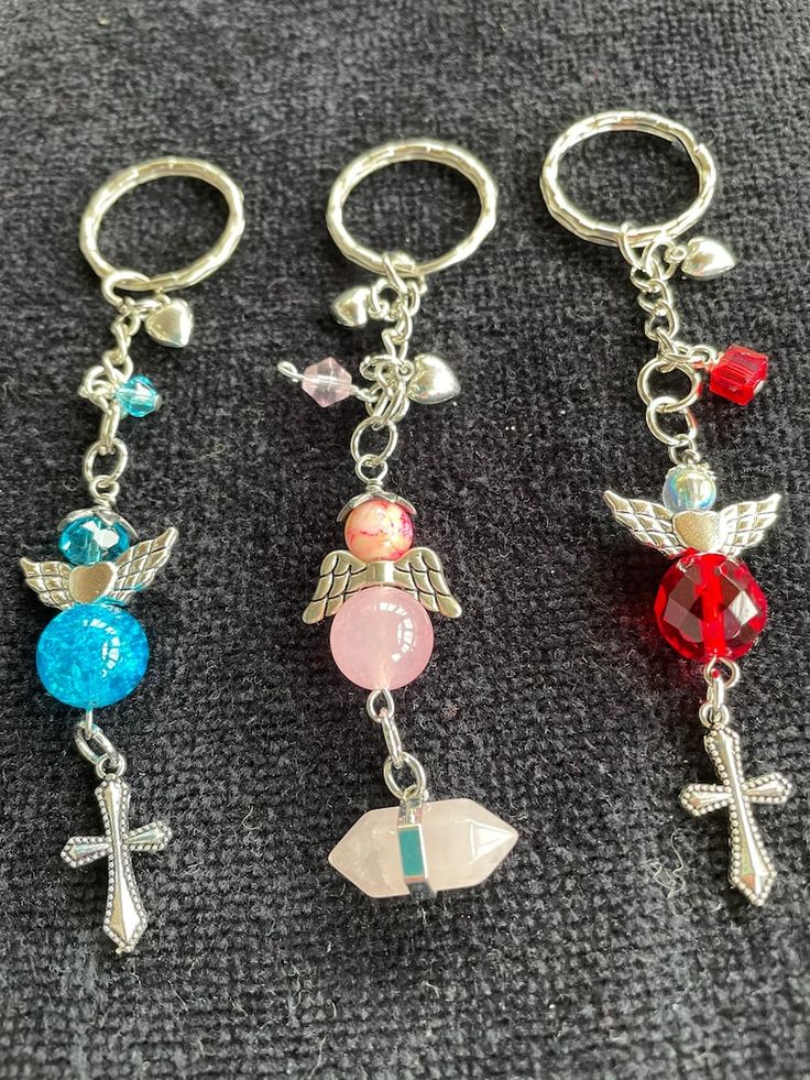 three key chains with charms on them sitting on a gray surface next to each other