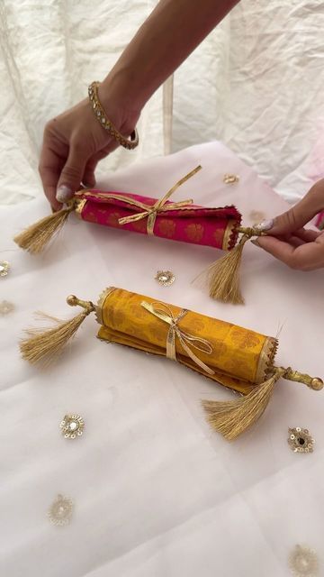 two women are making decorative items out of fabric and gold thread on a white table cloth