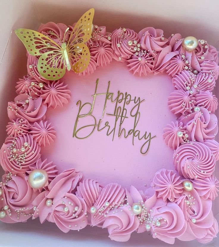 a pink birthday cake in a box with butterflies on top and flowers around the edges