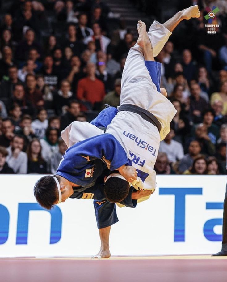 a man doing a handstand on top of another man in front of an audience