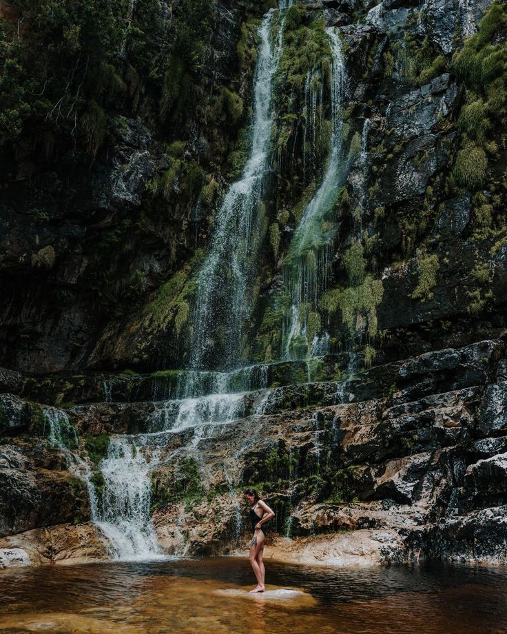 a person standing in the water near a waterfall