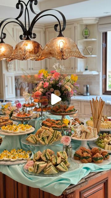 a table filled with lots of food on top of a kitchen counter next to a chandelier