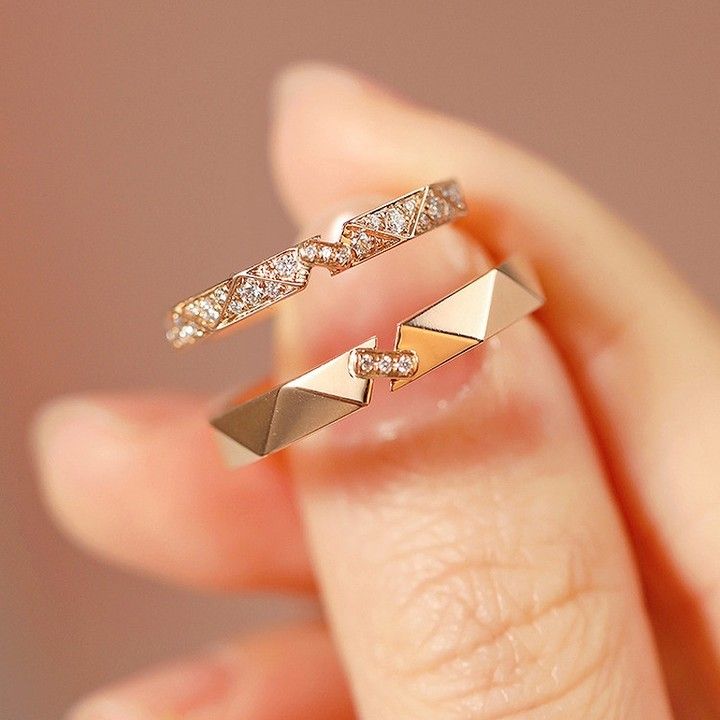 a woman's hand holding two gold rings with diamonds on each one and an arrow ring in the middle