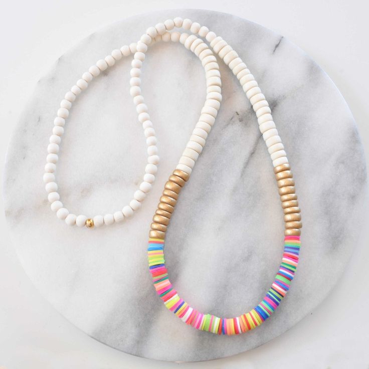 Get ready for summer with this wood beaded necklace! A mix of natural wood and bright heishi beads and in an easy pull-over-the-head style, these are sure to brighten up all your shorts-and-flip-flops looks. HEISHI & WOOD BEAD NECKLACES + 8mm wooden beads - choose cream, whitewash, tan, or natural + vinyl heishi beads in a random pattern + gold-plated crimp with bead closure for a pull-over-the-head style + 28 inches long + all Libby & Smee necklaces come packaged in a clear resealing bag for st Cheap Rainbow Heishi Beads Jewelry, Cheap Heishi Beads Necklaces For Vacation, Cheap Colorful Heishi Bead Necklaces, Cheap Green Necklace With Heishi Beads, Heishi Beads Wooden Necklaces, Adjustable Beaded Necklace With Wooden And Heishi Beads, Beach Wooden And Heishi Beads Necklaces, White Wooden Beaded Necklaces For Beach, Heishi Bracelets