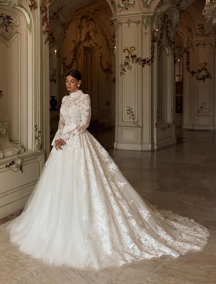 a woman in a white wedding dress standing next to a wall with chandeliers