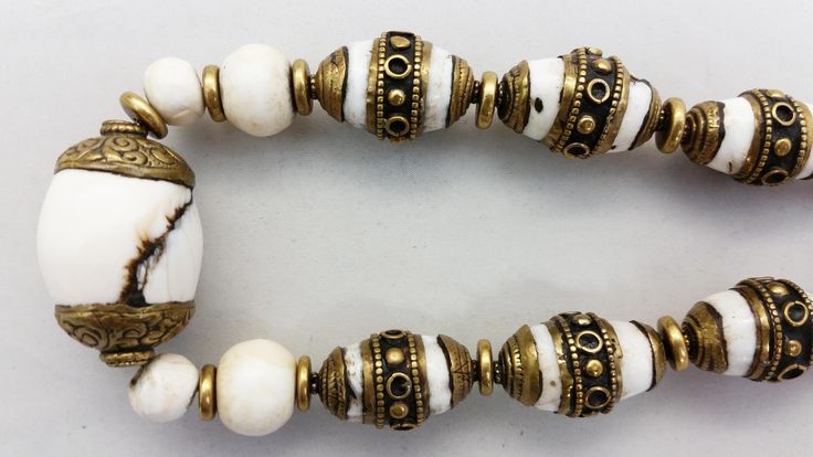 "This custom handmade necklace was made by jewelry artist Jacki Marsh. The beautiful white beads and the white beads with the brass caps in this necklace are sacred chank shells from Tibet / Nepal. Sacred chank shell (Turbinella Pyrum Linne) has been revered for thousands of years, since at least 2000 B.C. Chank shell is revered in Tibet, India, Nagaland and China. It is used by Hindus and Buddhists in rites and religious ceremonies. Tibetan men and women wear jewelry all of their lives for ador Artisan White Gemstone Beads Necklaces, Artisan White Necklaces With Gemstone Beads, Spiritual White Necklaces For Rituals, Spiritual White Necklace For Rituals, White Adjustable Spiritual Shell Necklace, White Hand-strung Bohemian Beaded Necklaces, White Adjustable Shell Necklace Spiritual Style, White Oval Beads Artisan Jewelry, White Hand-strung Festival Jewelry