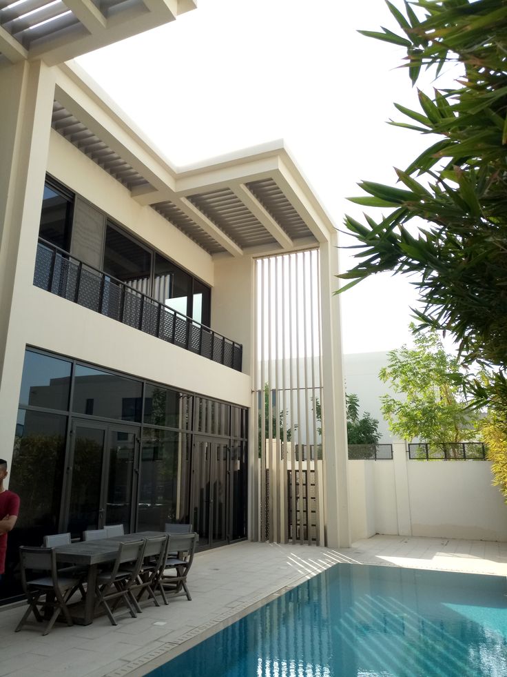 a man standing in front of a swimming pool next to a building with an open patio