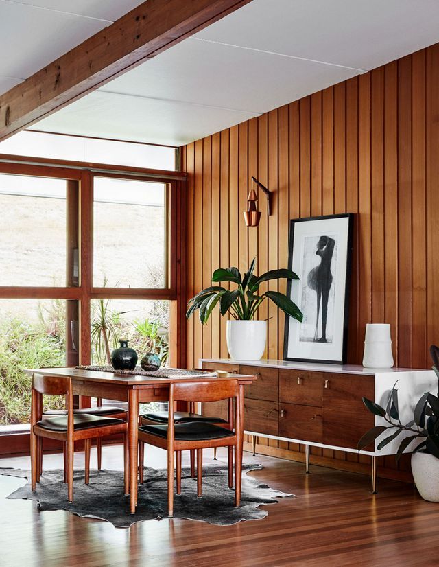 a dining room with wood paneling and large windows