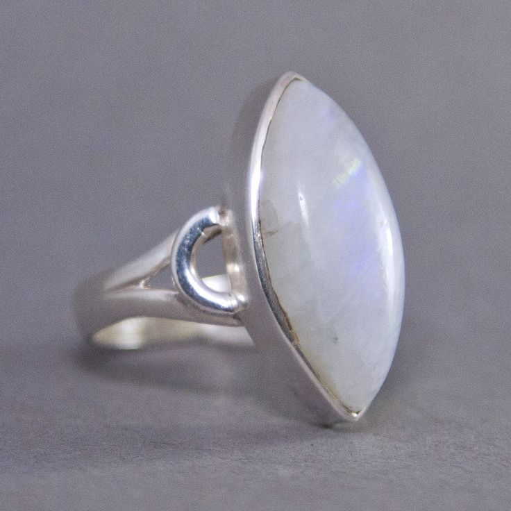 SKU: SS-048Material: 925 stamped sterling silverGemstone(s): Rainbow Moonstone (N)Gemstone Dimensions: 10 X 22 X 4 mmRing Size: US 7.5Weight: 5.9 gramsThis graceful Rainbow Moonstone cabochon ring features a marquise Rainbow Moonstone with a curved motif on its sides and a split shank band. The Rainbow Moonstone is a mostly opaque white with a subtle blue and orange fire that shows throughout the ring. Simple yet elegant! Marquise White Sterling Silver Ring, Marquise Sterling Silver Ring In White, Sterling Silver Oval Cabochon Moonstone Ring, White Moonstone Ring With Large Stone In Sterling Silver, Oval Cabochon Moonstone Ring In Sterling Silver, White Sterling Silver Gemstone Ring, Sterling Silver Moonstone Ring With Large Stone, Sterling Silver Cabochon Moonstone Ring For Anniversary, Anniversary Sterling Silver Cabochon Moonstone Ring