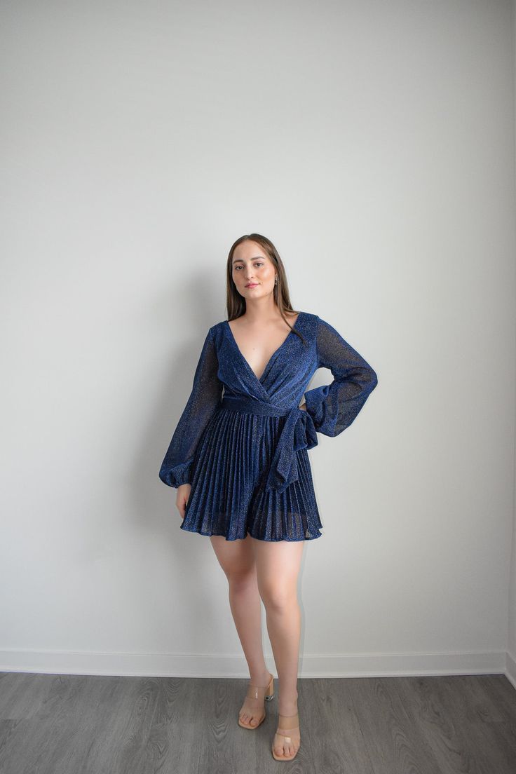 Navy Dress Romper with sparkling belt and long sleeves to dazzle at any formal event. Featuring an adjustable belt and a plunging v-neckline, you can elevate your look with sky-high heels or simply make it a more relaxed ensemble for at-home soirées. Crafted from a lightweight Polyester, this Navy Dress Romper is the epitome of grace and sophistication. Size guide: The First Model is 5'6" and wearing size Small. The Second model is wearing a size small Cocktail V-neck Belted Mini Dress, Glamorous Spring V-neck Party Dress, Glamorous Spring Evening V-neck Dress, Elegant V-neck Belted Dress For Evening, Formal V-neck Belted Dress, Formal Belted V-neck Dress, Formal V-neck Dress With Belt, Chic V-neck Party Dress With Tie Waist, V-neck Party Dress With Belt