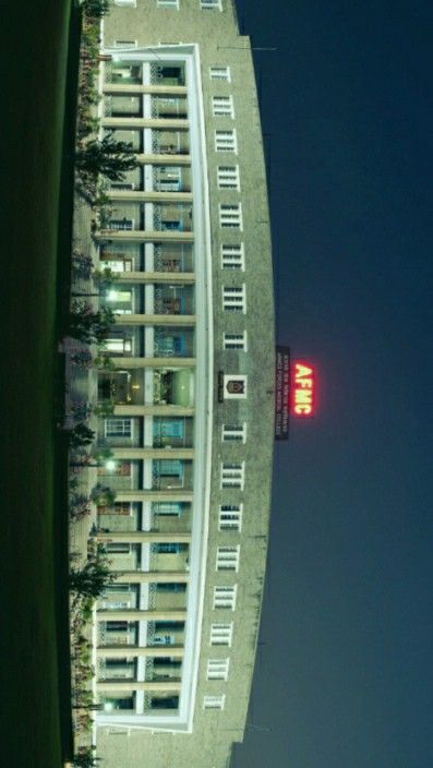 a tall building with many windows next to a red sign on the side of it