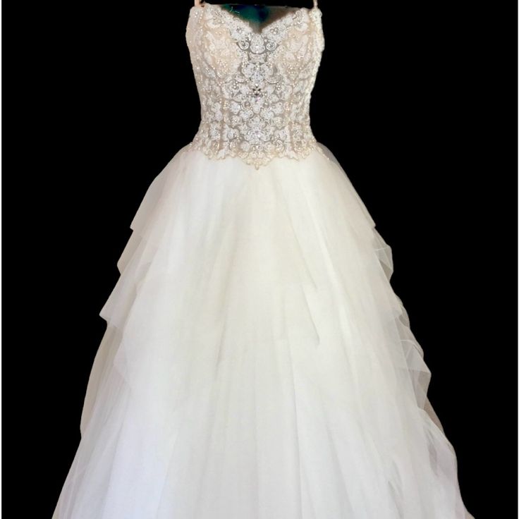 a white wedding dress on display in front of a black background