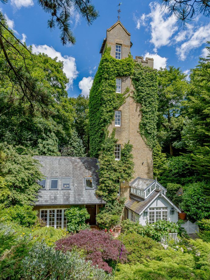 an old house with ivy growing on it's side and trees surrounding the building