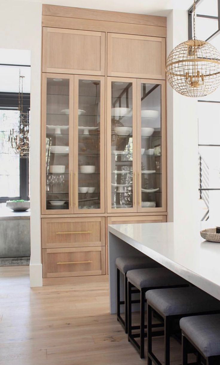 a kitchen with wooden cabinets and stools in front of the counter top, along with a chandelier hanging from the ceiling