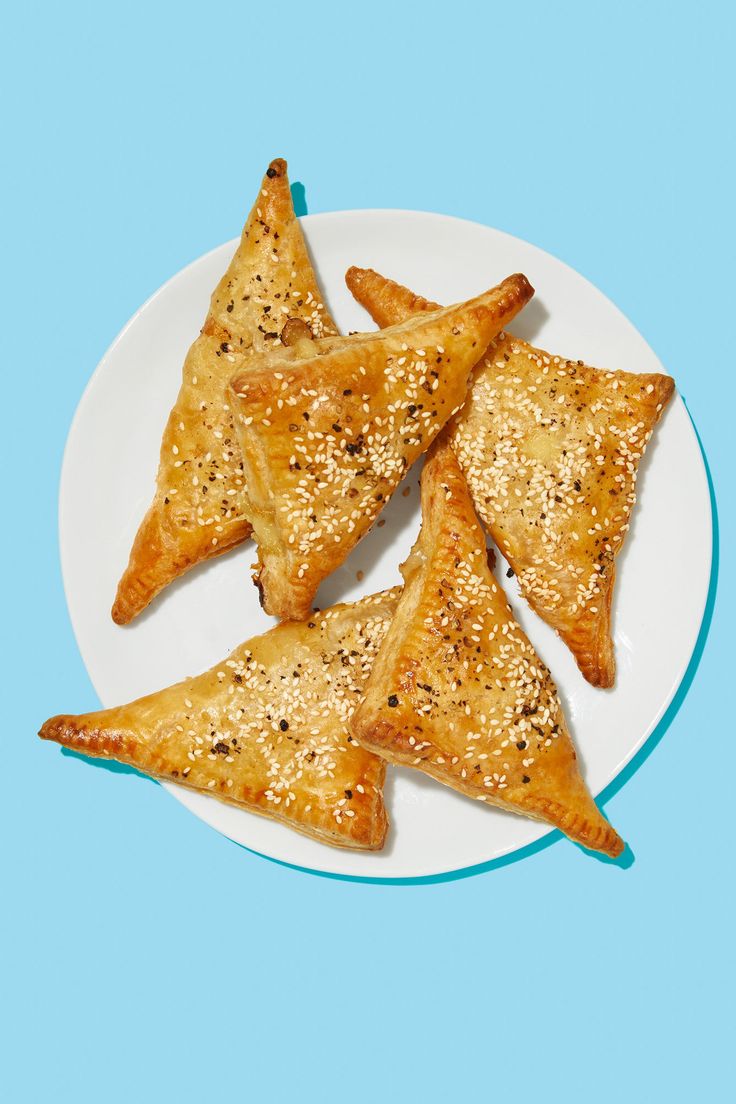 three pieces of pastries on a white plate with blue and green border around them