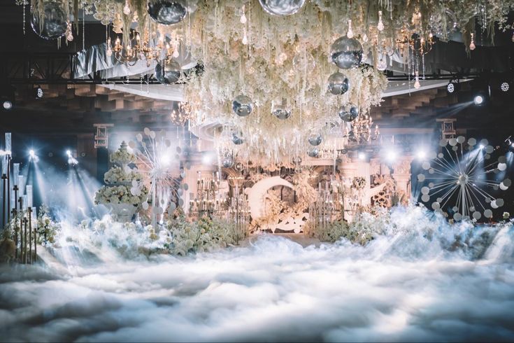 a stage set with chandeliers and lights in the middle of it, surrounded by clouds