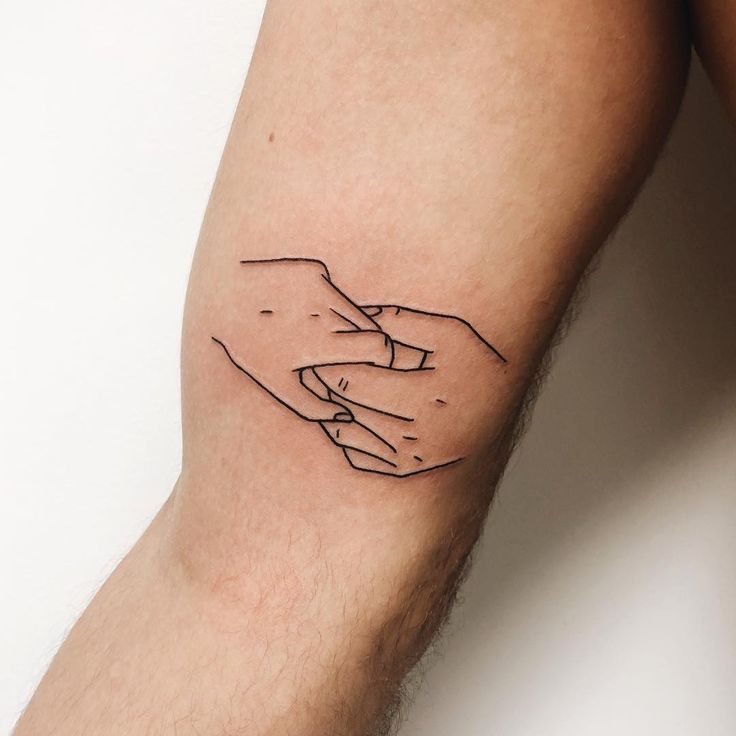 two hands touching each other on the left side of the arm, with black ink