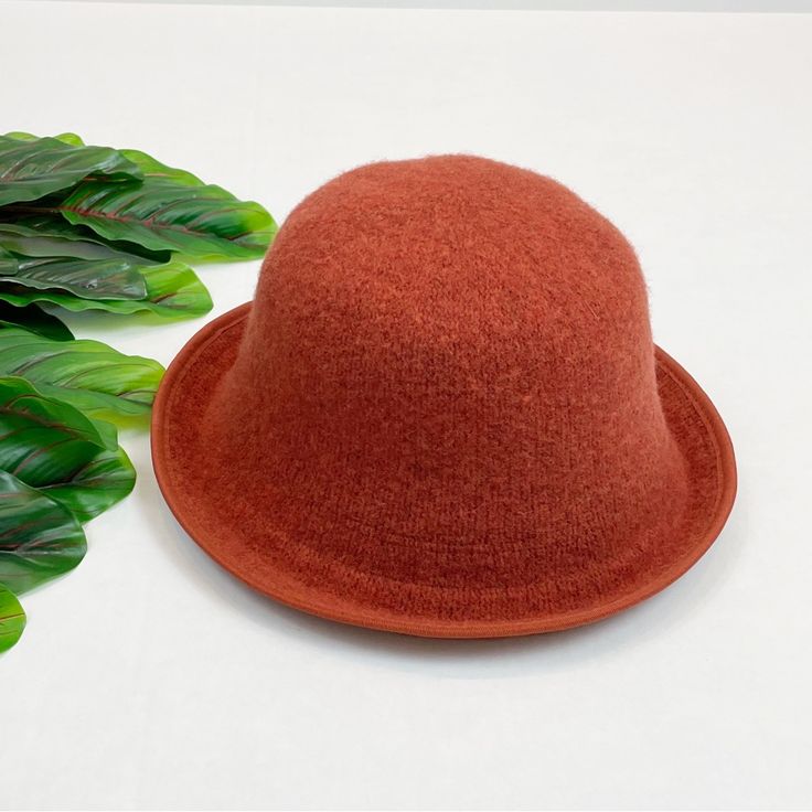 a red hat sitting on top of a white table next to green leafy plants