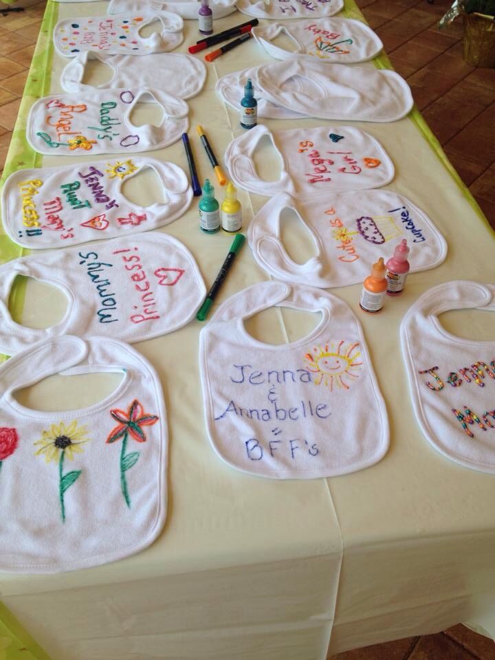 several bibs are laid out on a table with crayons and paintbrushes