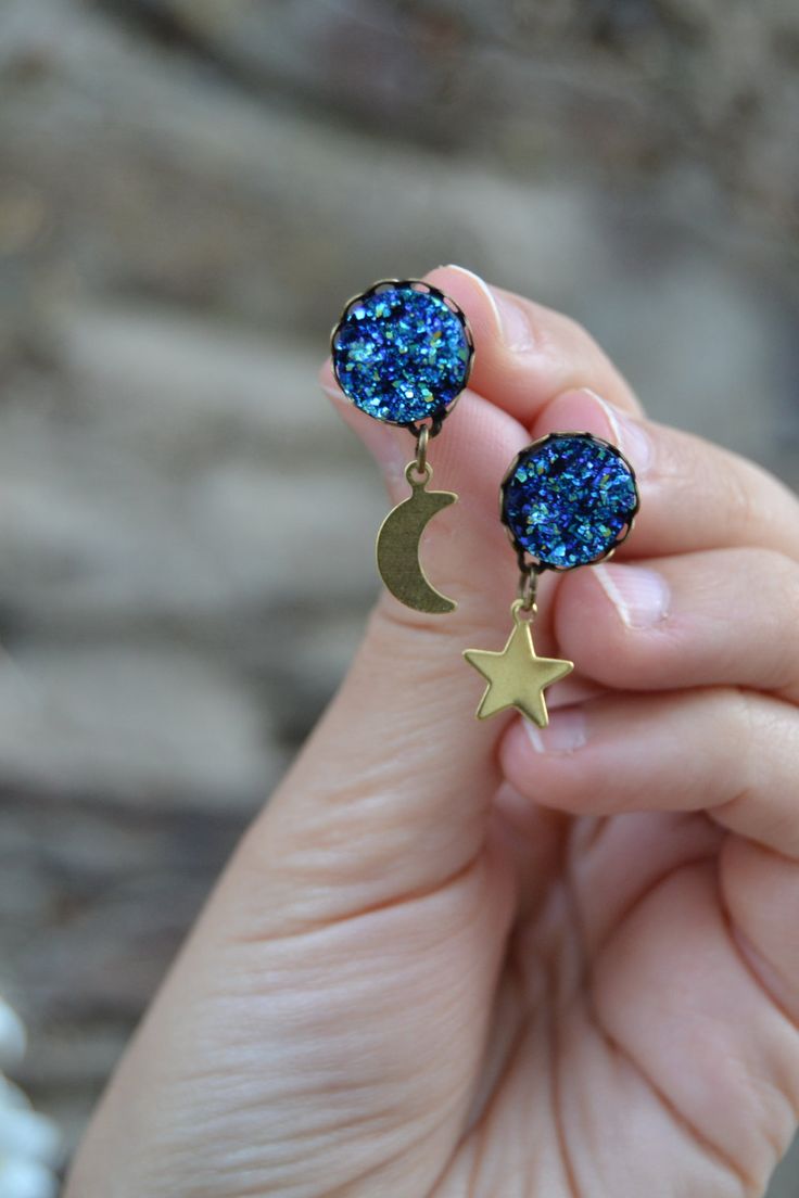 PLEASE read my shop announcement before placing an order so you know what to expect right now. Plus, when ordering from outside Europe, don't forget to provide a phone number for the courier to ensure the fastest and smoothest delivery. Sparkling peacock / sapphire blue druzy stud earrings with golden brass dangling moon and star. Dainty and edgy at the same time, elegant Boho Chic style. Antiqued bronze lightweight posts, rubber backings Cabochon base is about 12 mm, 0.47 inches Quality sinthet Blue Star Charm Drop Earrings, Blue Drop Earrings With Star Charm, Peacock Sapphire, Mismatch Earrings, Moon And Star Earrings, Moon Studs, Druzy Earrings, Mismatched Earrings, Gold Moon