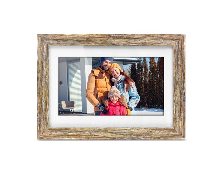 a family standing in front of a house with snow on the ground and trees behind them