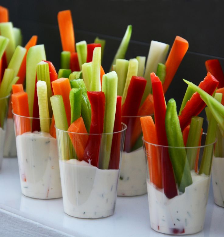 small cups filled with different types of veggies on top of a white table