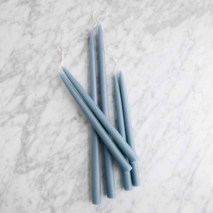 three blue candles sitting on top of a marble counter