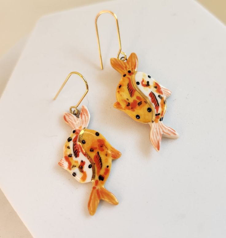 "Porcelain ceramic earrings, hand painted with a variety of glazes, including 22k gold luster accents. Hook is plated 18k gold over raw brass. Ceramic pieces are painted solid gold on the back. Each earring measures approximately 2.25\" long and weighs less than a quarter of an ounce.  Patterns will vary from photo: every piece is made to order and painted patterns will not be identical. Production time is 2-3 weeks.  Earrings will ship wrapped in tissue paper in a box, suitable for gifting." Unique Gold Jewelry With Black Enamel, Hand Painted Yellow Gold Jewelry Gift, Hand Painted Yellow Gold Jewelry As Gift, Hand Painted Yellow Gold Jewelry For Gifts, Hand Painted Yellow Gold Jewelry As A Gift, Unique Gold Enamel Jewelry, Orange Enamel Earrings As A Gift, Orange Enamel Earrings For Gift, Orange Enamel Earrings For Gifts