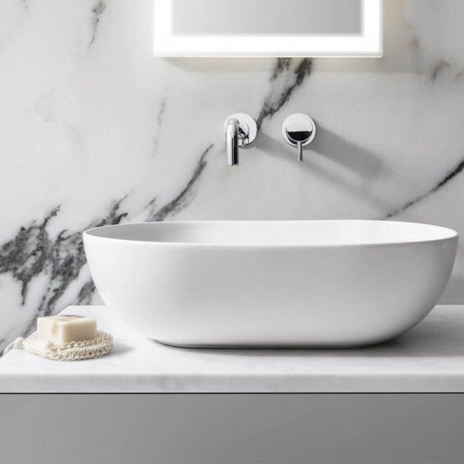 a white sink sitting on top of a counter next to a mirror and light fixture