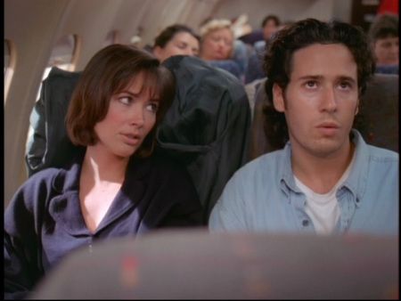 a man and woman sitting on an airplane looking at something in the distance with other people behind them