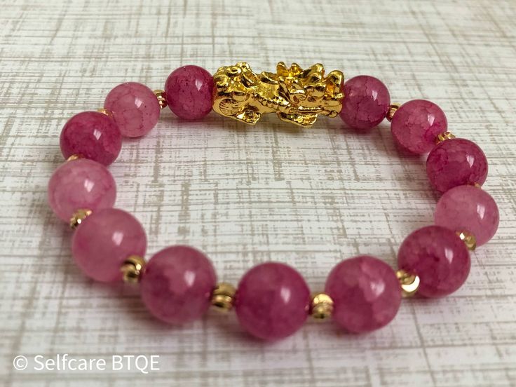 This Feng Shui bracelet is made with Pink Jade Natural Stone and is a beautiful work of artistry. Our Pixiu or Pi Yao bracelet, also known as the wealth and good luck bracelet, comes in two pink shades: Flamingo and Bubblegum pink. If you are looking for a sparkly girly addition to your collection, then this is what you need. The Feng Shui Bracelet or Pixiu Bracelet is a powerful piece of jewelry used in Asian cultures to attract wealth, good luck, and fortune into their homes, businesses, or wo Gold Jade Crystal Bracelet Spiritual Style, Gold Jade Crystal Bracelet With Spiritual Style, Gold Jade Crystal Bracelet, Spiritual Style, Jade Bracelets With Polished Beads As A Gift, Jade Bracelets With Polished Beads For Gifts, Spiritual Gemstone Bracelets For Good Luck, Spiritual Gemstone Bracelet For Good Luck, Adjustable Gemstone Beads Bracelets For Good Luck, Gold Jade Crystal Bracelet Gift